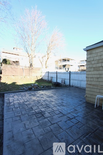 A backyard with a patio and a tree.