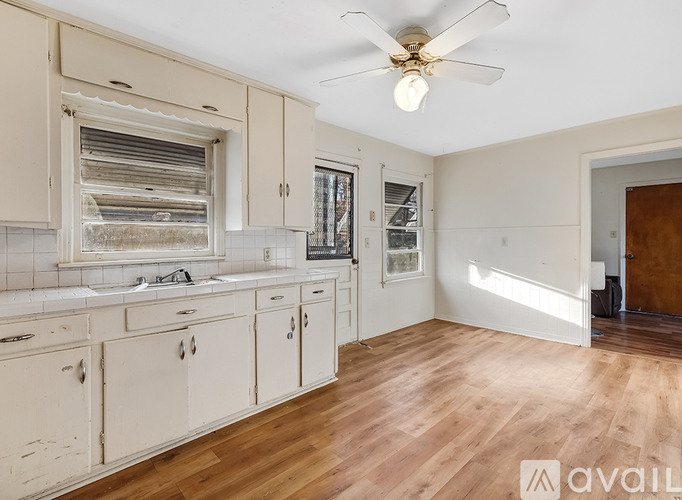 A kitchen with wooden floors and white cabinets.