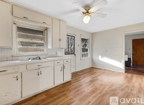 A kitchen with wooden floors and white cabinets.