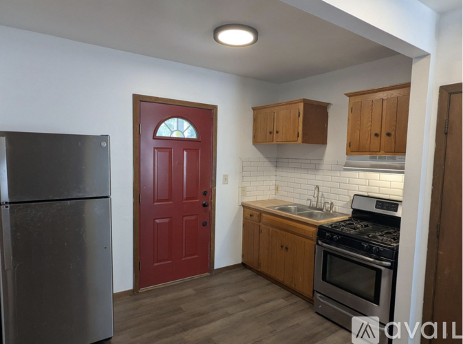 A kitchen with a red door and wooden cabinets.