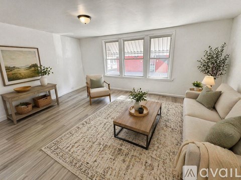 A living room with a large rug, a sofa, a chair, and a coffee table.