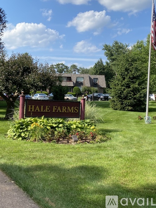 A sign that says "HALE FARMS" in front of a green lawn.