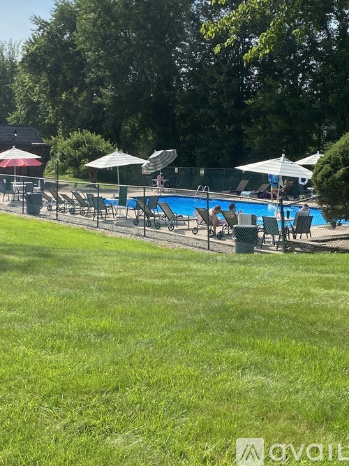 A pool surrounded by lawn chairs and umbrellas.