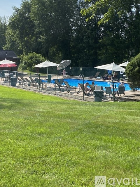 A pool surrounded by lawn chairs and umbrellas.