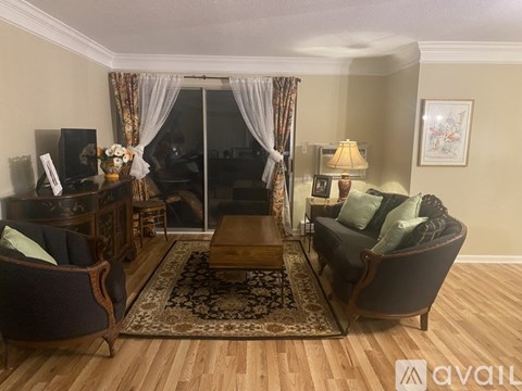A living room with a brown sofa, a wooden coffee table, and a glass door leading to a balcony.