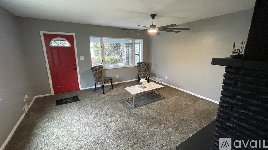 A room with a red door and a fan on the ceiling.