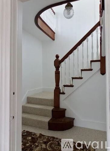 A staircase with a wooden handrail and beige carpeted steps.