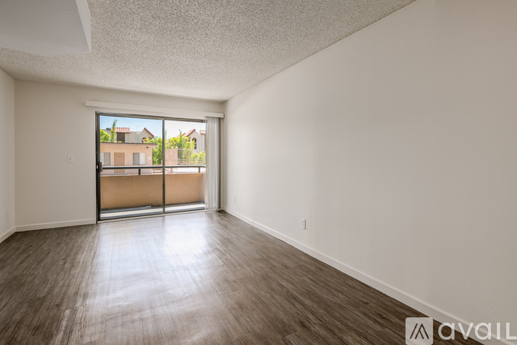 Empty room with wooden floor and sliding glass doors.
