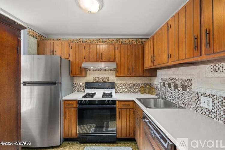 A kitchen with wooden cabinets and a stainless steel refrigerator.