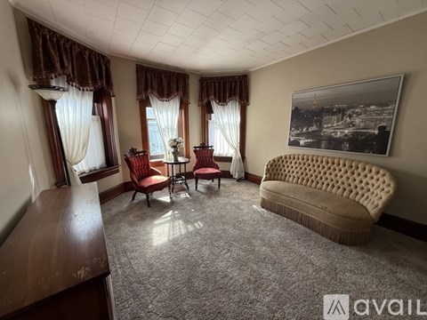 A living room with a sofa, two chairs, and a table with a vase of flowers on it.