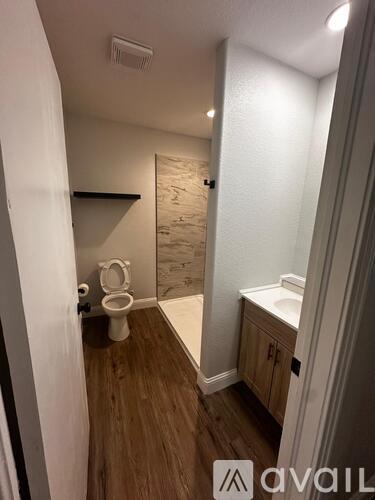 A small bathroom with a toilet, sink, and wooden floors.