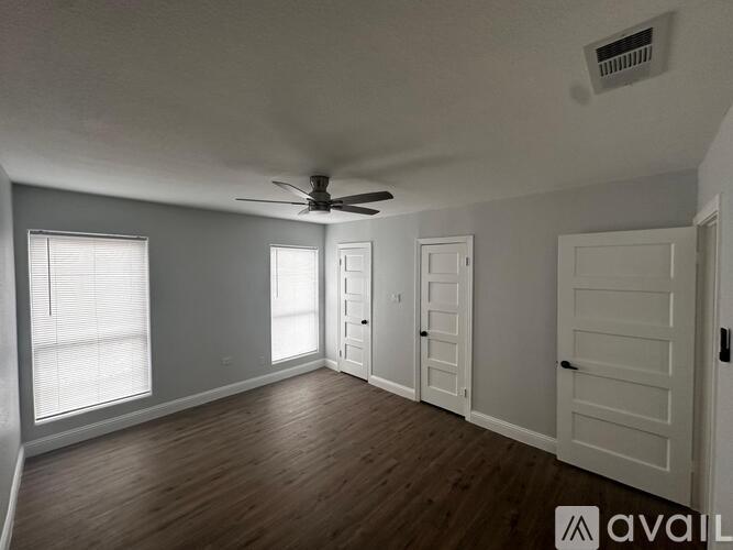 A spacious room with a ceiling fan and wooden flooring.