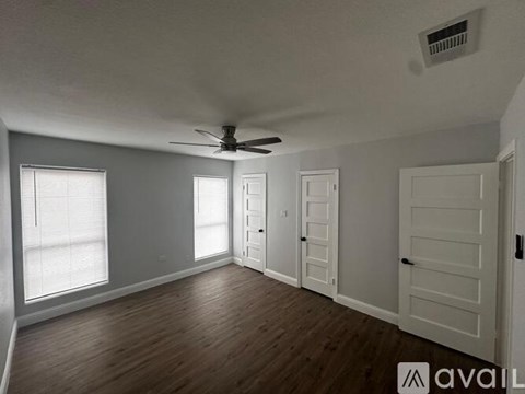 A spacious room with a ceiling fan and wooden flooring.