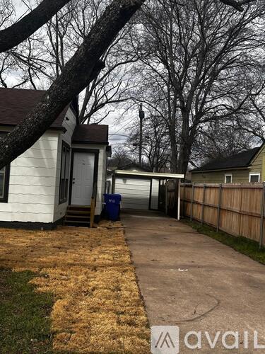 A house with a white exterior and a brown roof is shown with a tree branch in the foreground.