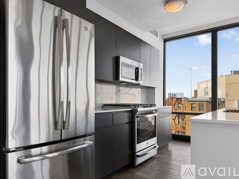 A modern kitchen with a stainless steel refrigerator and black appliances.