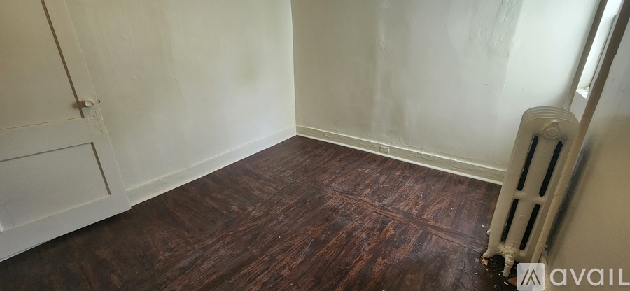 A room with a wooden floor and a white radiator.