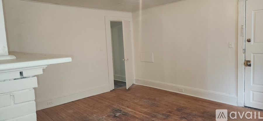A room with a fireplace on the left and a door on the right.