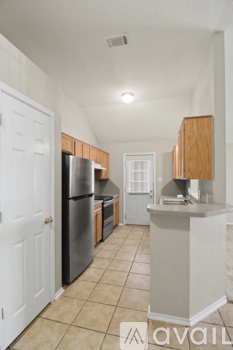 A kitchen with a refrigerator, sink, and cabinets.