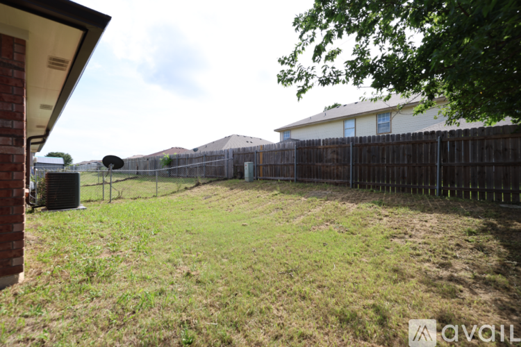 A backyard with a wooden fence and a grassy area.