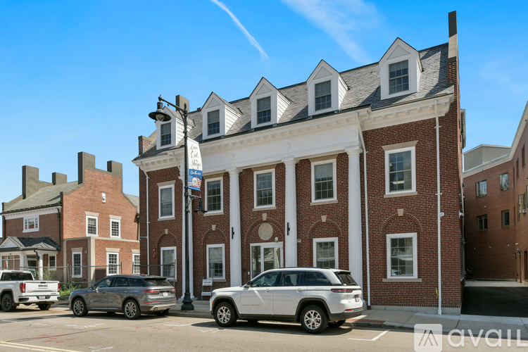 A silver SUV is parked in front of a red brick building.