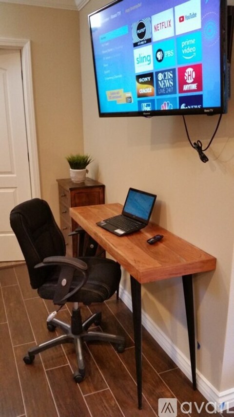 A black chair is in front of a wooden desk with a laptop on it.