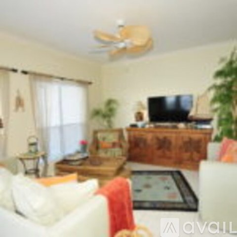 A living room with a white couch and a wooden dresser.