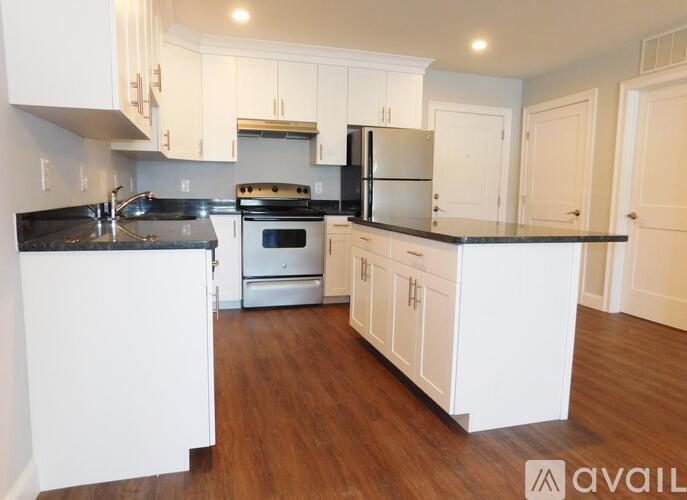 A kitchen with white cabinets and a black countertop.