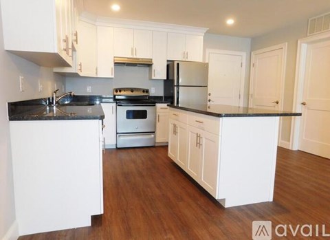 A kitchen with white cabinets and a black countertop.
