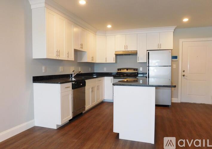 A kitchen with white cabinets and a black countertop.