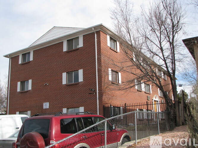 A red vehicle is parked in front of a brick building.