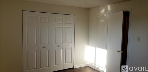 A room with a white door and a brown floor.
