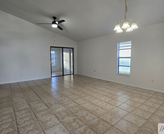 A spacious room with tiled flooring and a ceiling fan.