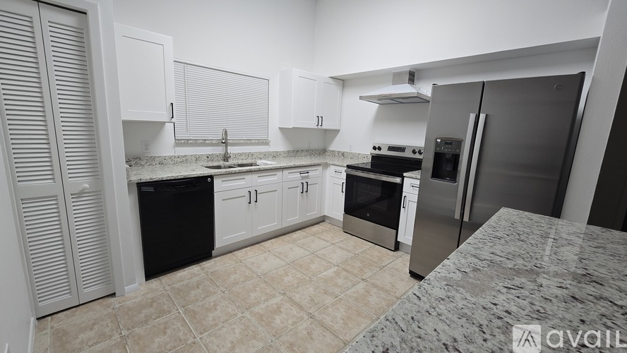 A kitchen with white cabinets and a black fridge.