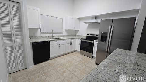 A kitchen with white cabinets and a black fridge.