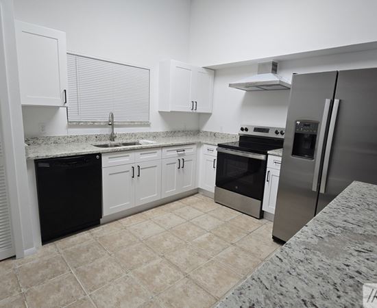 A kitchen with white cabinets and a black fridge.