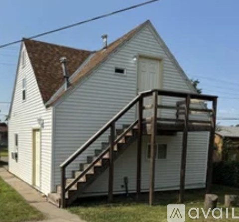 A white house with a brown roof and a staircase leading to the door.