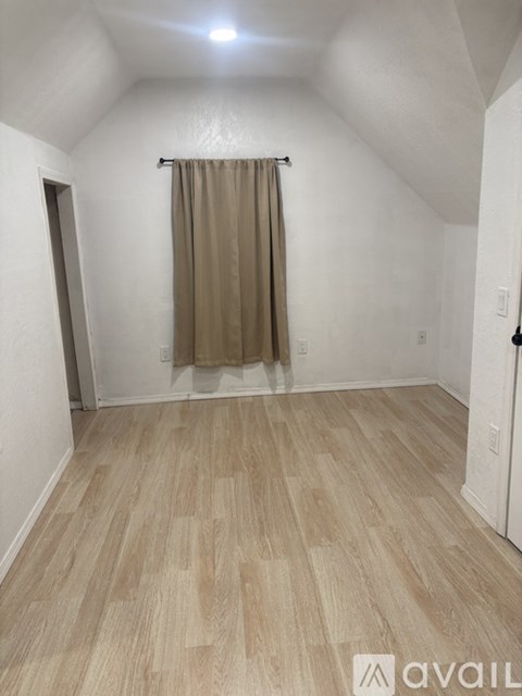 A room with a beige curtain and wooden flooring.