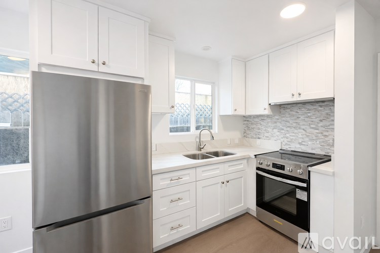 A modern kitchen with a stainless steel refrigerator and white cabinets.