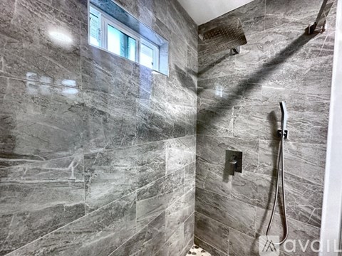 A bathroom with a marble tile wall and a window.