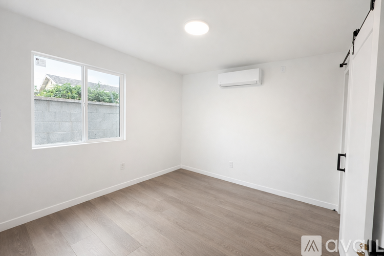 A spacious room with a window and a wall-mounted air conditioner.