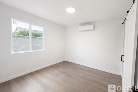 A spacious room with a window and a wall-mounted air conditioner.