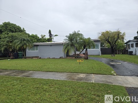 A house with a driveway and a tree in front of it.