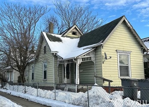 A house with a snow-covered roof and a fence in front.