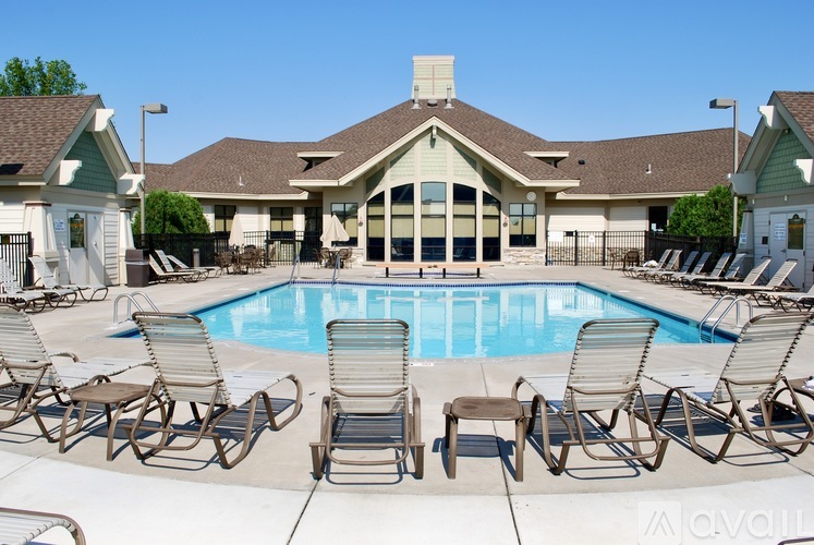 A pool surrounded by chairs in front of a building.