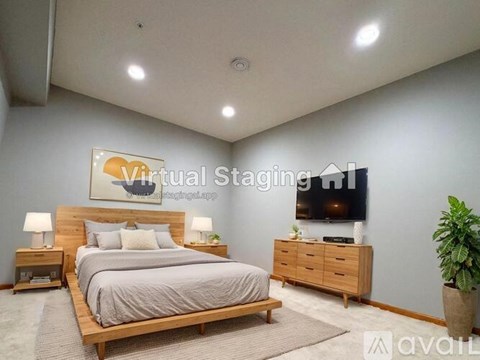 A bedroom with a bed, nightstands, and a plant.
