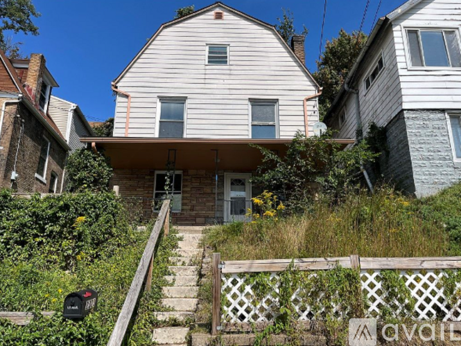 A house with a white facade and a mailbox on the stairs.