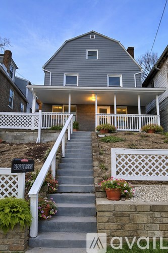 A house with a white facade and a mailbox on the stairs.