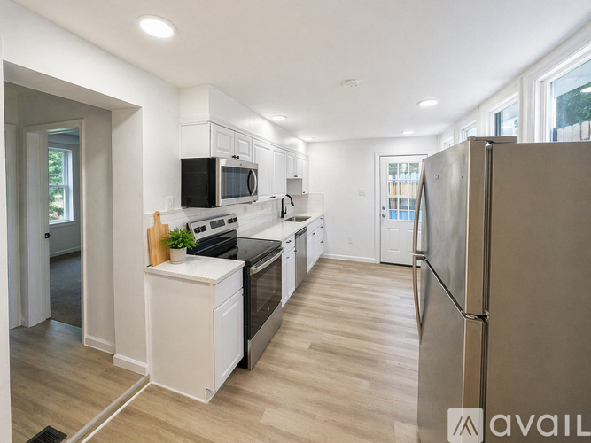 A large empty room with wooden floors and a kitchen area in the background.