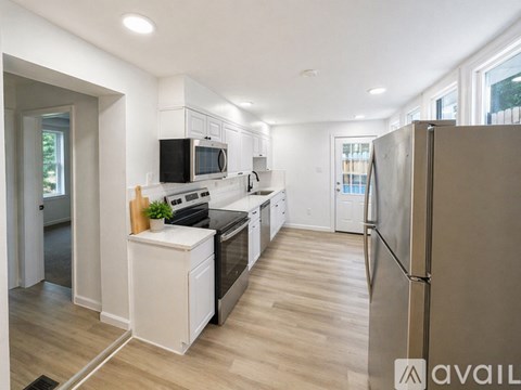 A large empty room with wooden floors and a kitchen area in the background.