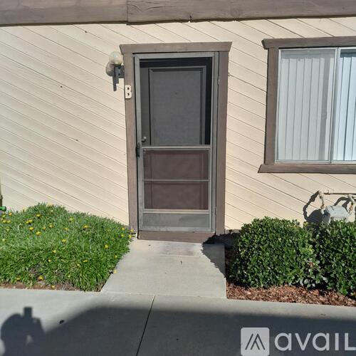 A house with a brown door and a window with white curtains.